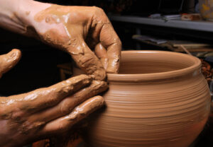 Potter at his wheel finishing a pot.